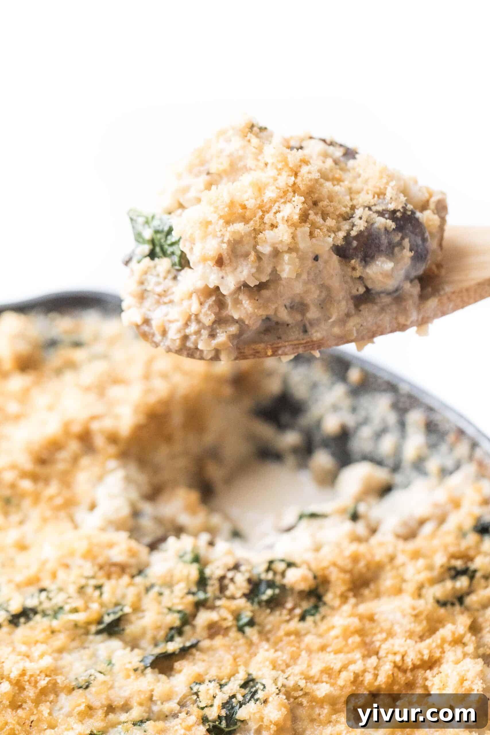 Savory Whole30 Keto Creamy Chicken Cauliflower Bake 3 spoon scooping out creamy chicken cauliflower rice casserole in a cast iron skillet, showing the rich texture