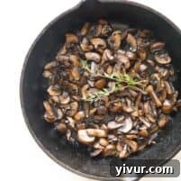 A close-up of the finished Whole30 + Keto Sauteed Mushrooms, garnished with fresh thyme and ready to serve.
