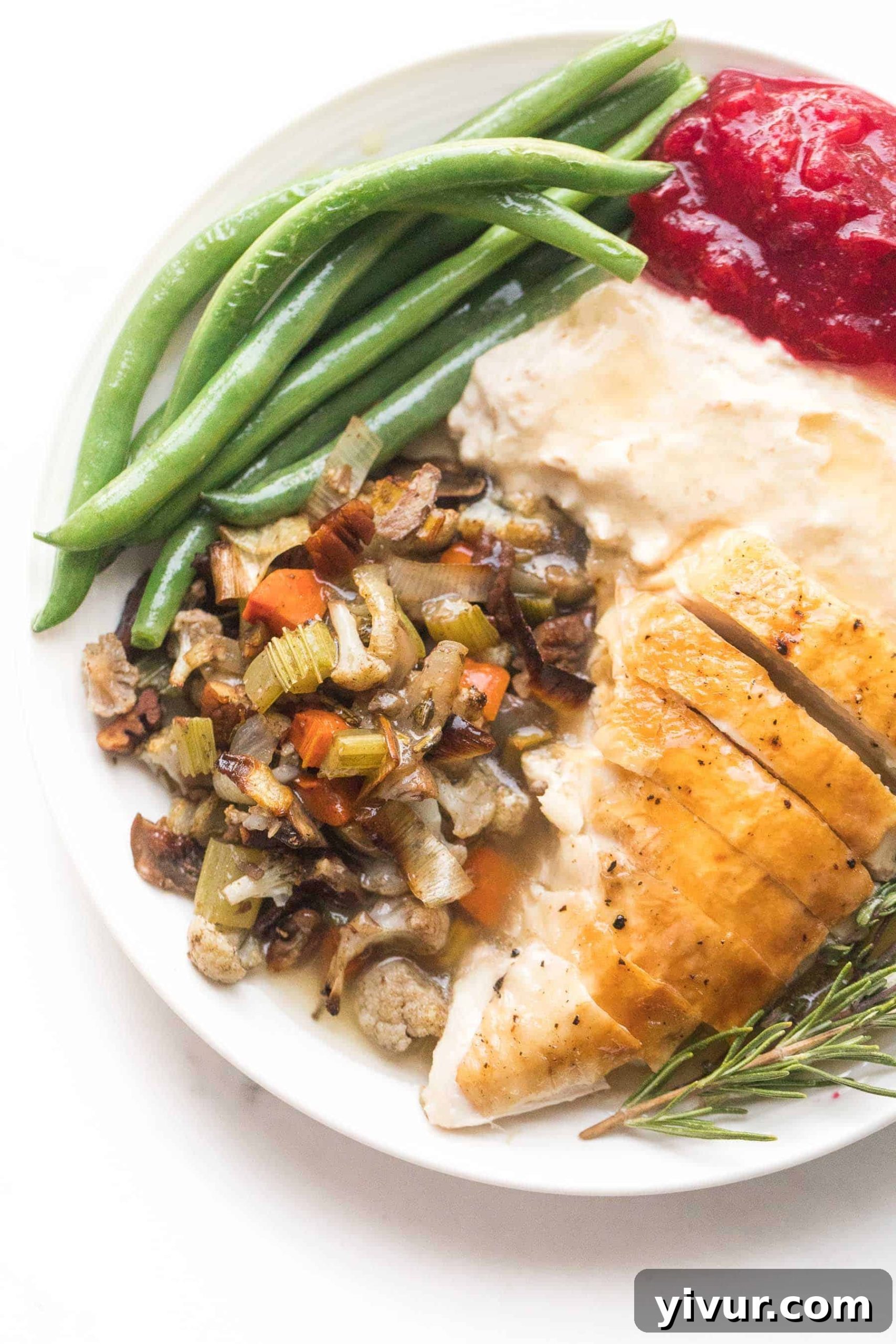 keto thanksgiving dinner plate with turkey, cauliflower stuffing, green beans, mashed cauliflower, and keto cranberry sauce