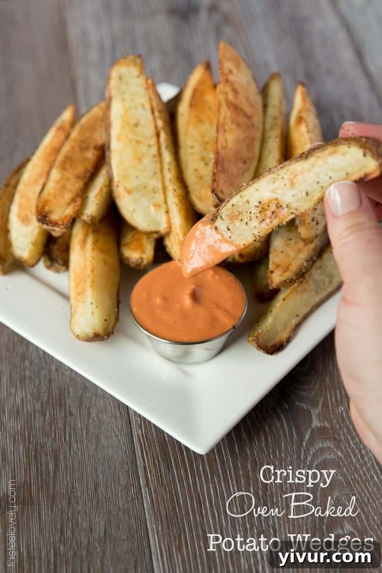 Perfectly Roasted Potato Wedges 2 Golden brown crispy oven baked potato wedges with a vibrant spicy sriracha ketchup dipping sauce on the side
