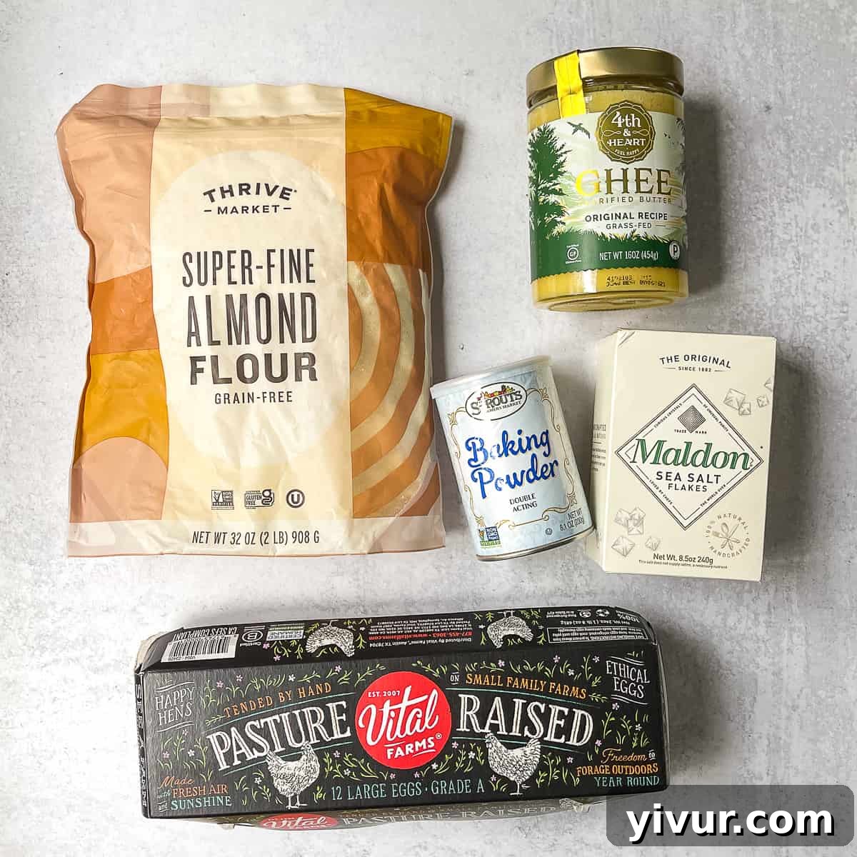 A flat lay photograph showcasing the 5 simple ingredients for low-carb biscuits: almond flour, eggs, baking powder, sea salt, and ghee.