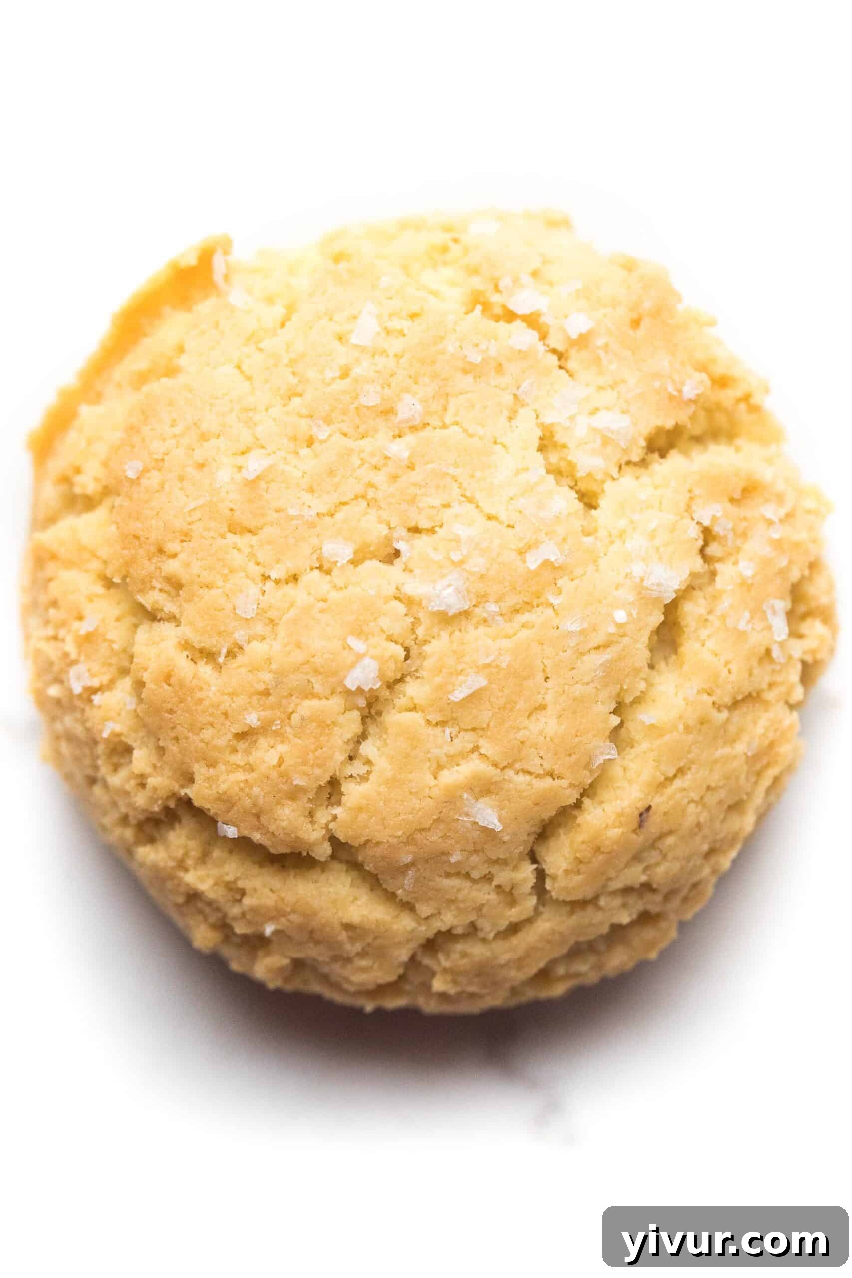 A single almond flour keto biscuit placed on a white background, showcasing its golden color and texture.