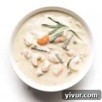 creamy chicken chowder in a white bowl and background with sage garnish on top
