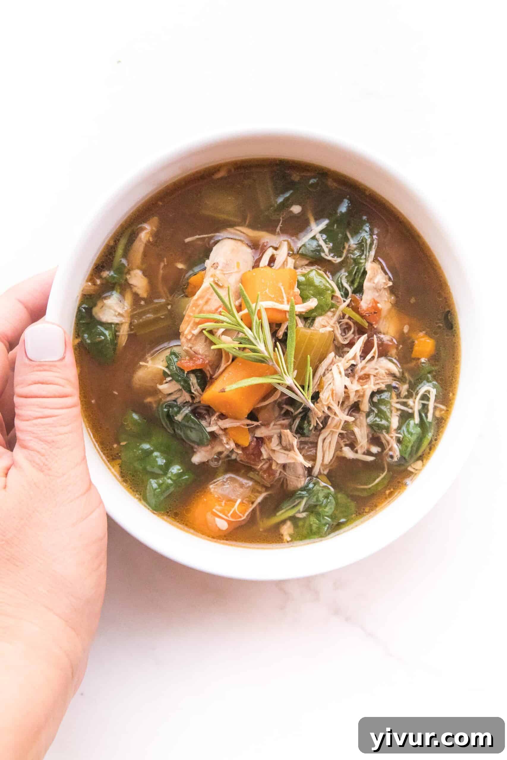 Hand holding a bowl of steaming Tuscan Chicken Soup, ready to be enjoyed