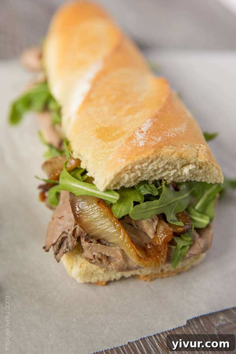 Ultimate Beef Dip Sandwich with Gruyere and Sweet Grilled Onions 3 Close-up of a delectable beef dip sandwich, showcasing layers of roast beef, melted Gruyere, and golden caramelized onions.