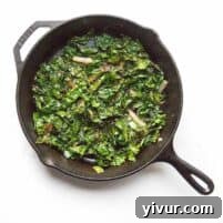 Sautéed kale in a cast iron skillet, garnished and ready to serve