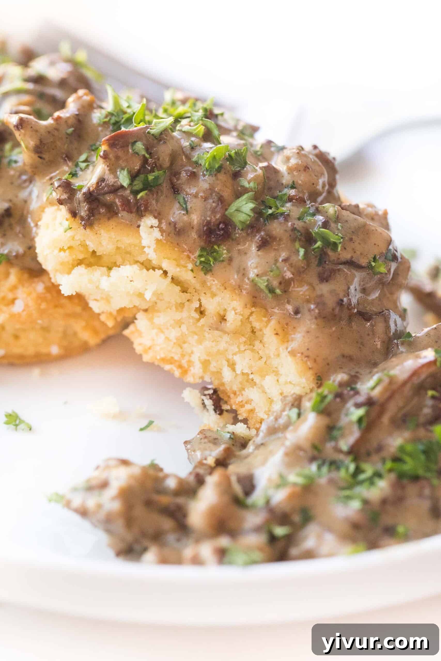 KETO BISCUITS AND GRAVY ON A WHITE PLATE
