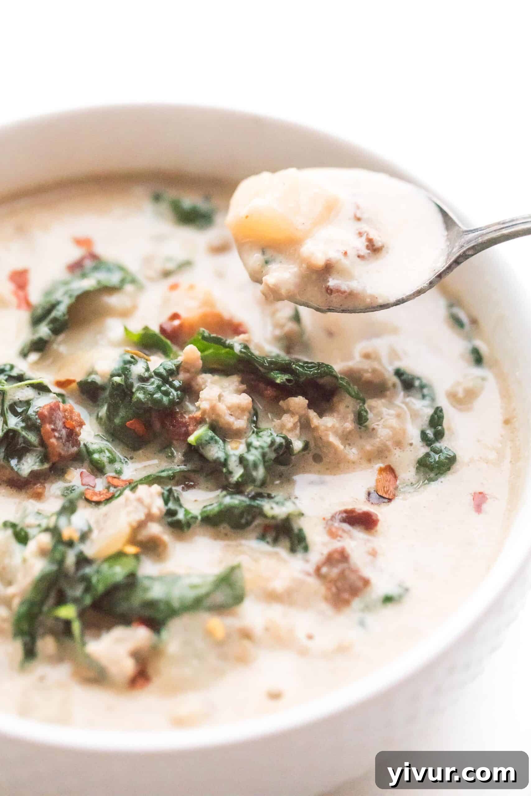 Creamy low-carb zuppa toscana in a bowl with a spoon, featuring turnips, sausage, and kale.