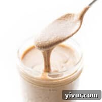 Spoon pouring mixed nut butter into a mason jar