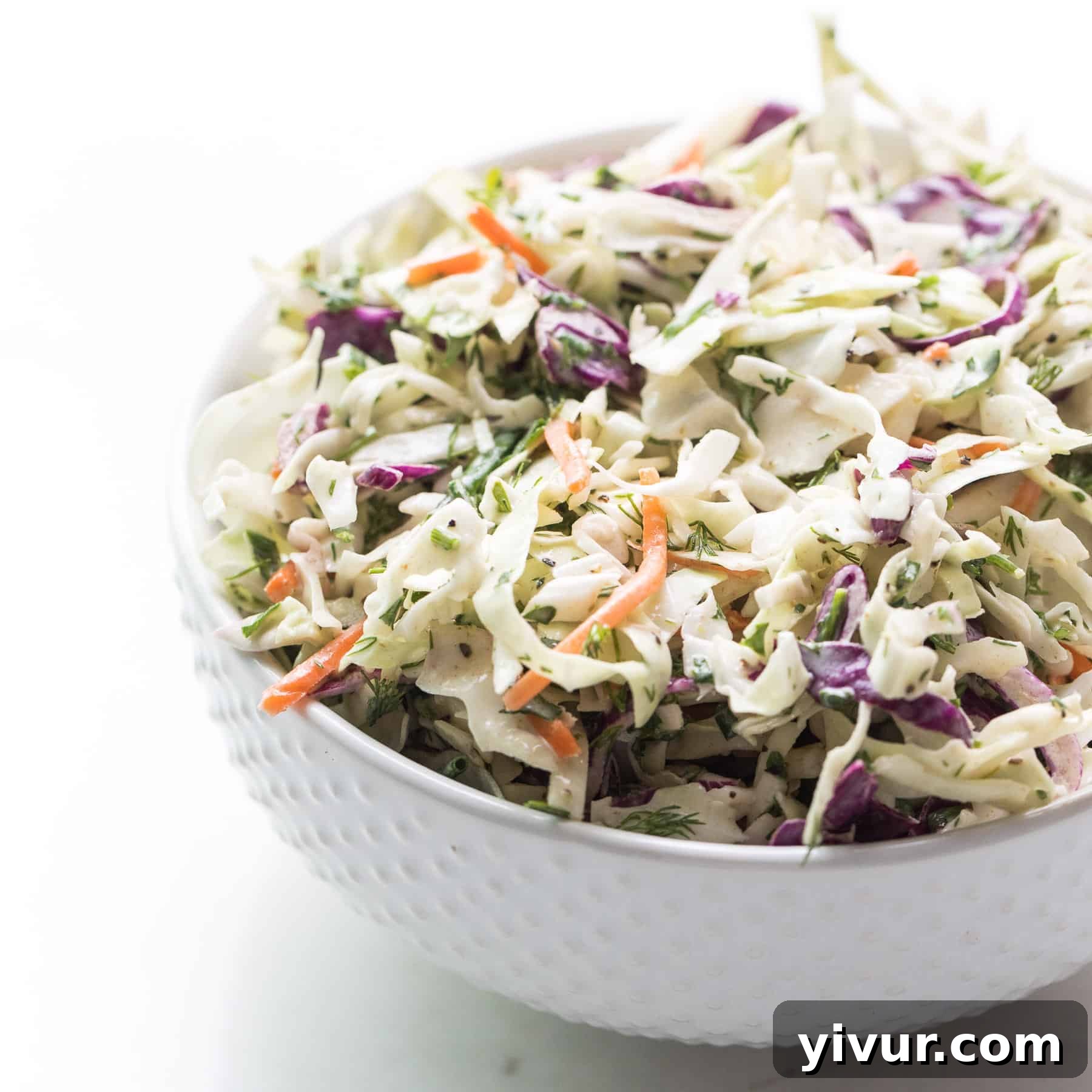 Fresh, vibrant herby lemon coleslaw in a white bowl, a refreshing and zesty low-carb side dish.