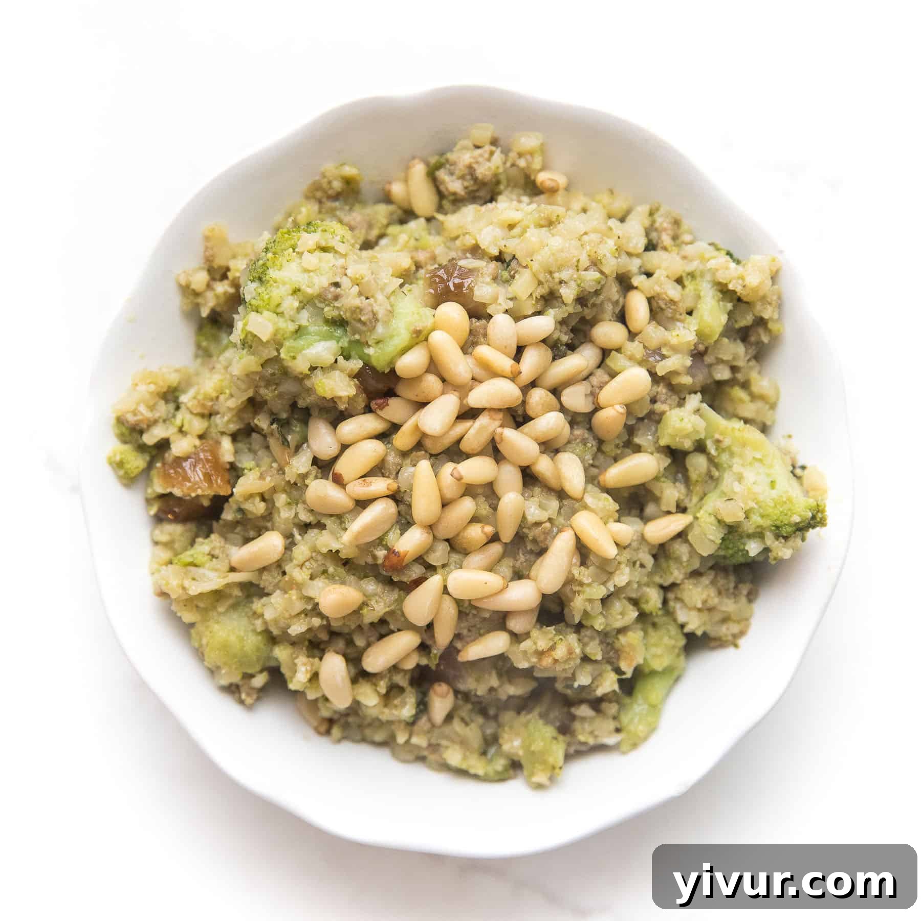Zesty Pesto Cauliflower Rice Stir Fry Whole30 Keto 2 pesto cauliflower rice, broccoli, meatballs and pinenuts in a white bowl