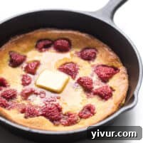 keto dutch baby pancake in a cast iron skillet with raspberries