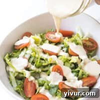 The Ultimate Dairy-Free Keto Caesar Dressing for Whole30 5 Pouring homemade dairy-free keto Caesar dressing over a fresh salad