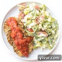 Crispy coated eggplant served alongside a fresh Caesar salad on a pristine white plate, the main image for the recipe