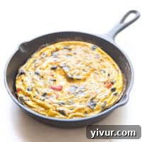 A delicious frittata in a cast iron skillet, set against a pristine white background, ready to be served.