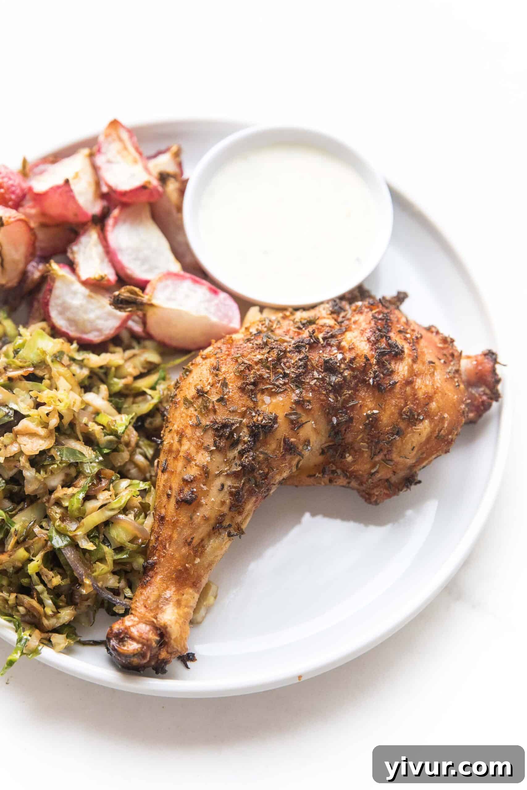Grilled Spatchcock Blackened Chicken served on a white plate with roasted radishes and shaved brussels sprouts.