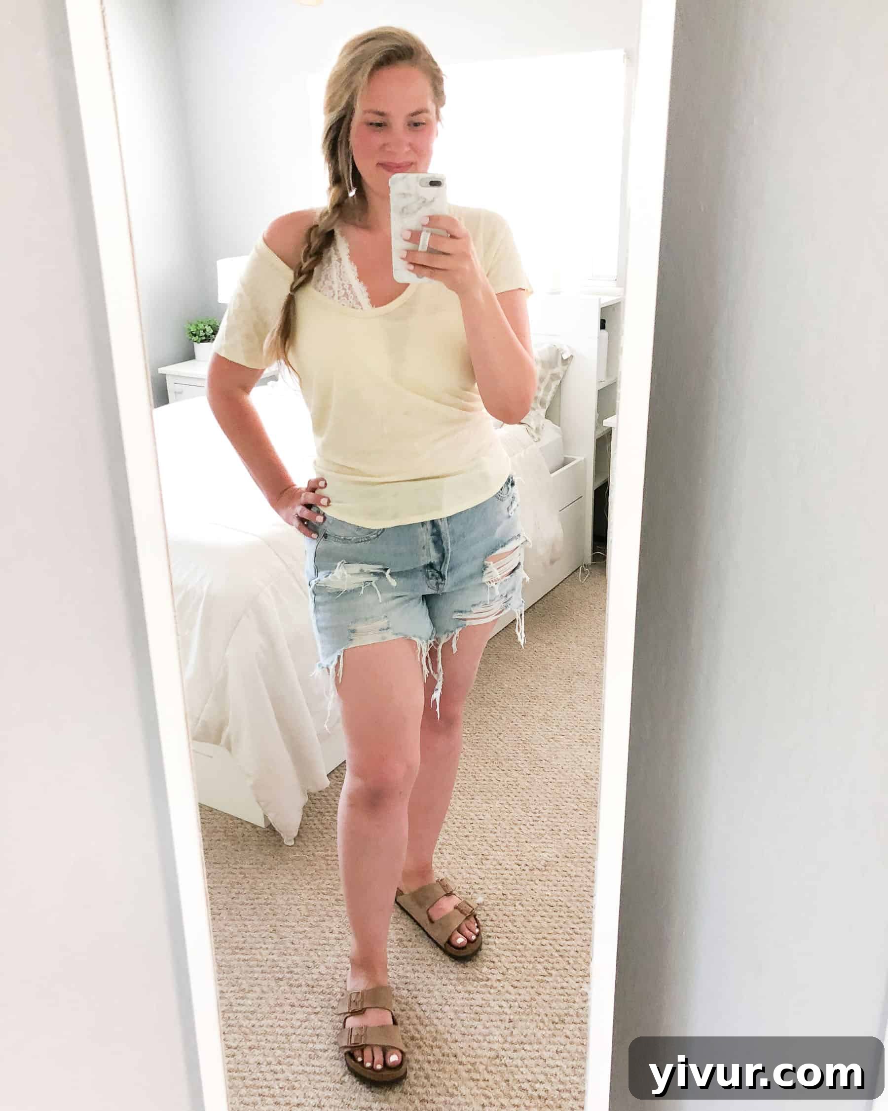 Curvy woman modeling everyday fashion basics including denim shorts, a V-neck tee, and Birkenstock sandals, exuding comfort and casual style.