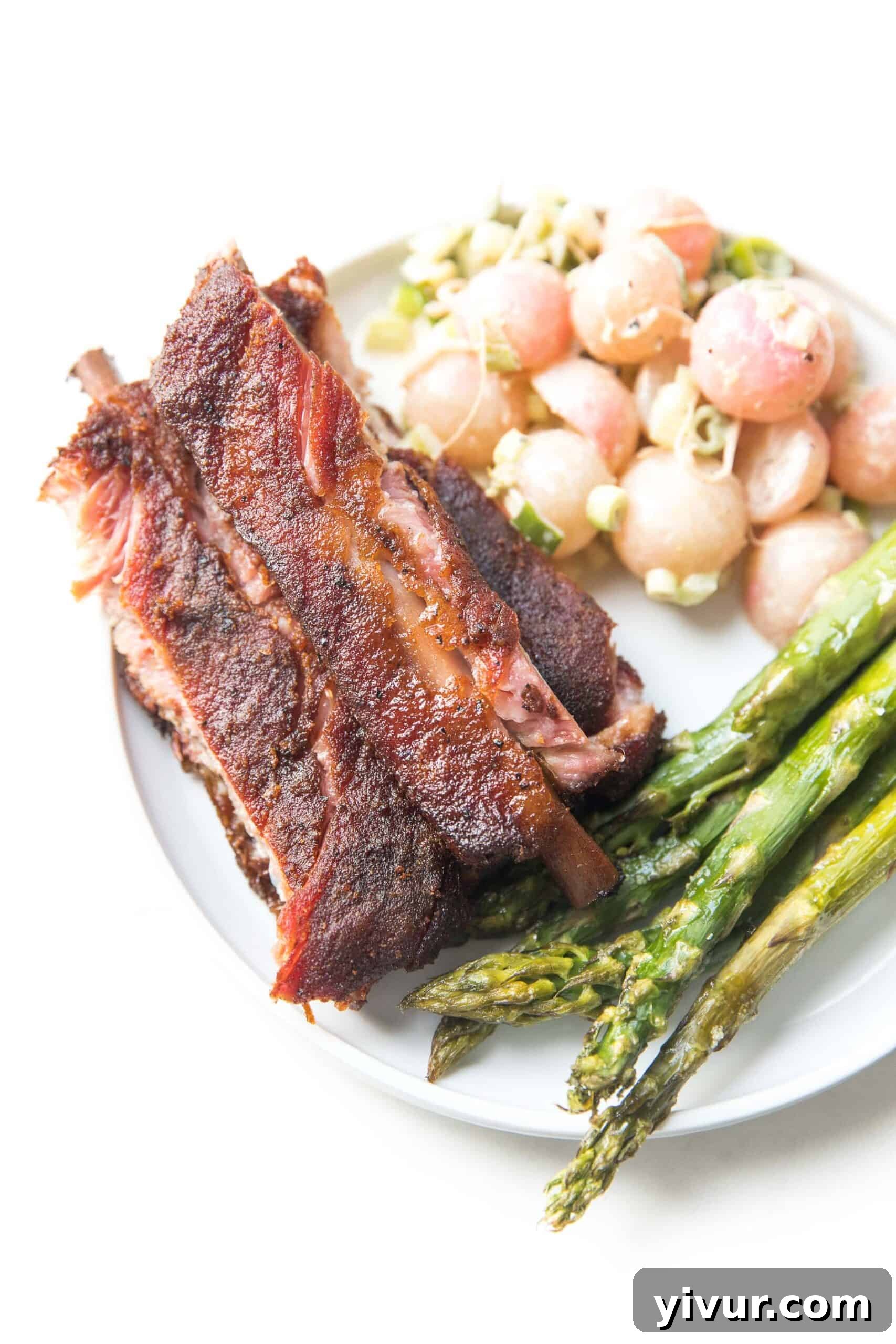 plate of ribs on a white background with asparagus and keto potato salad