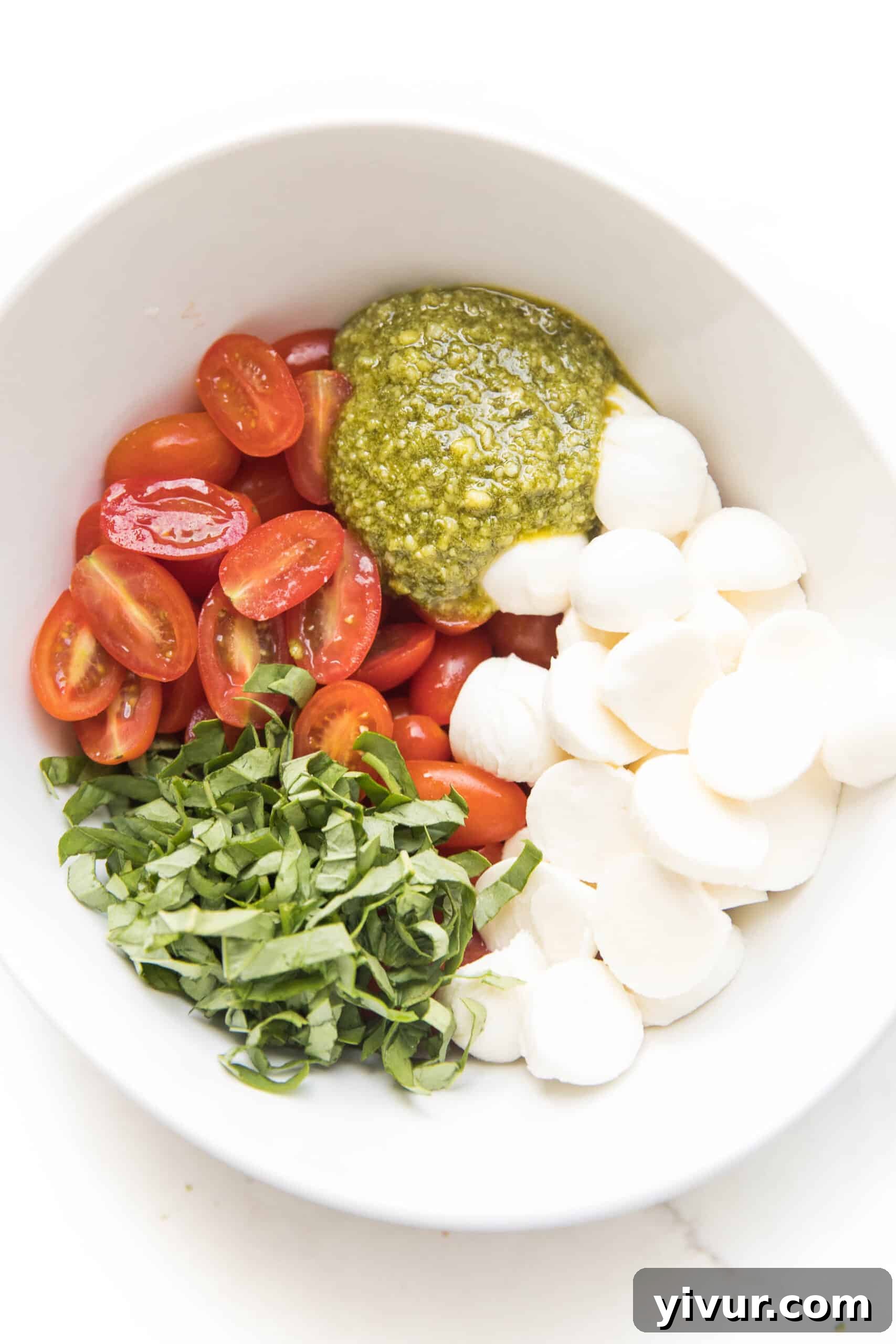Close-up view of the fresh and vibrant Pesto Caprese Salad, ready to be served in a rustic white bowl.
