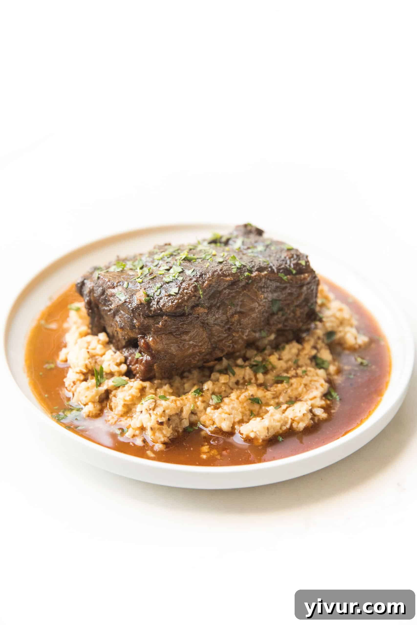 Melt-In-Your-Mouth Instant Pot Keto Short Ribs 4 Close-up shot of braised short ribs, showcasing their tender texture and rich color, accompanied by cauliflower rice risotto.