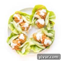 keto buffalo turkey meatballs on lettuce wraps topped with ranch dressing on a white plate and background