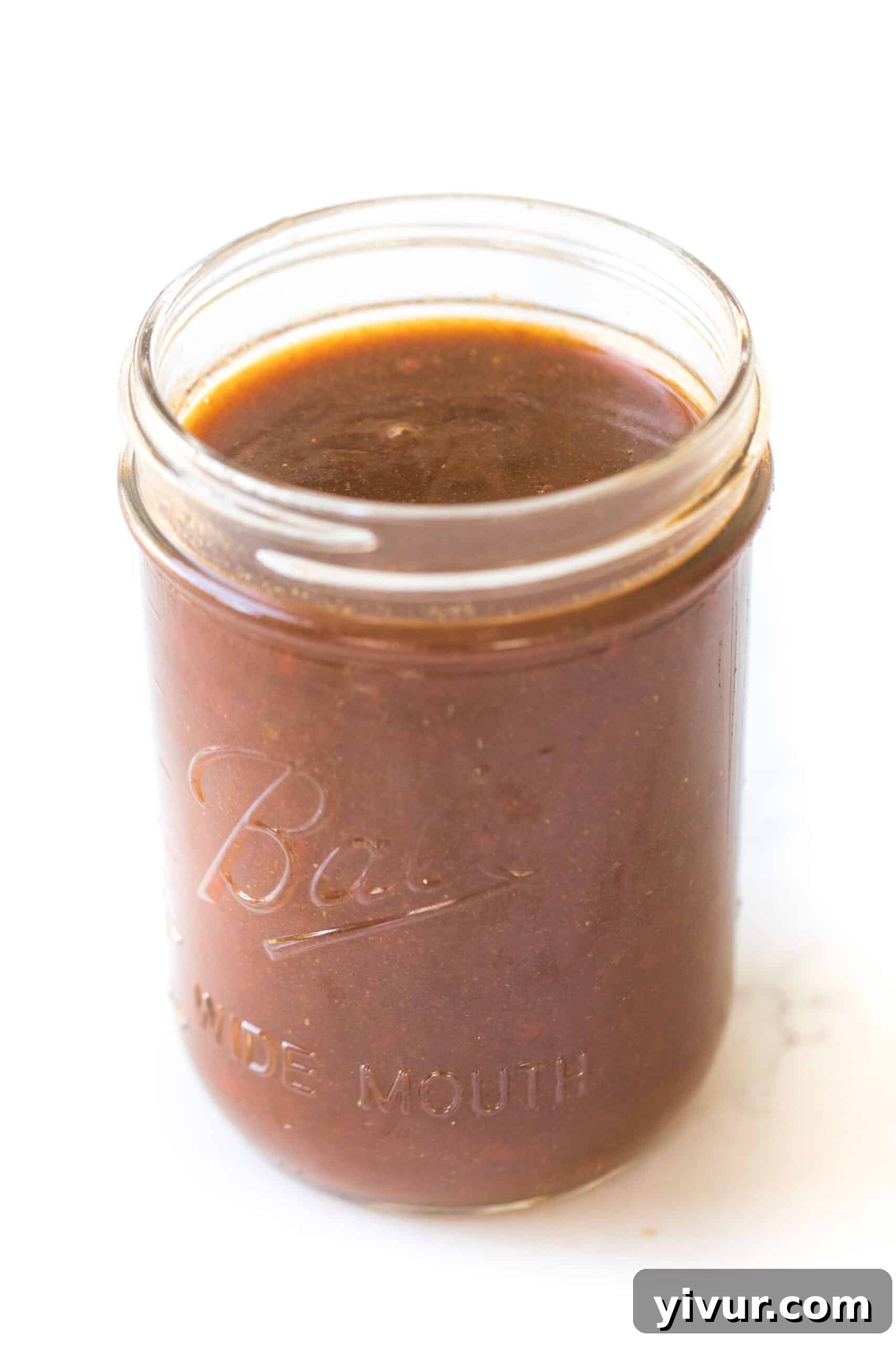 mason jar of homemade red enchilada sauce on a white background