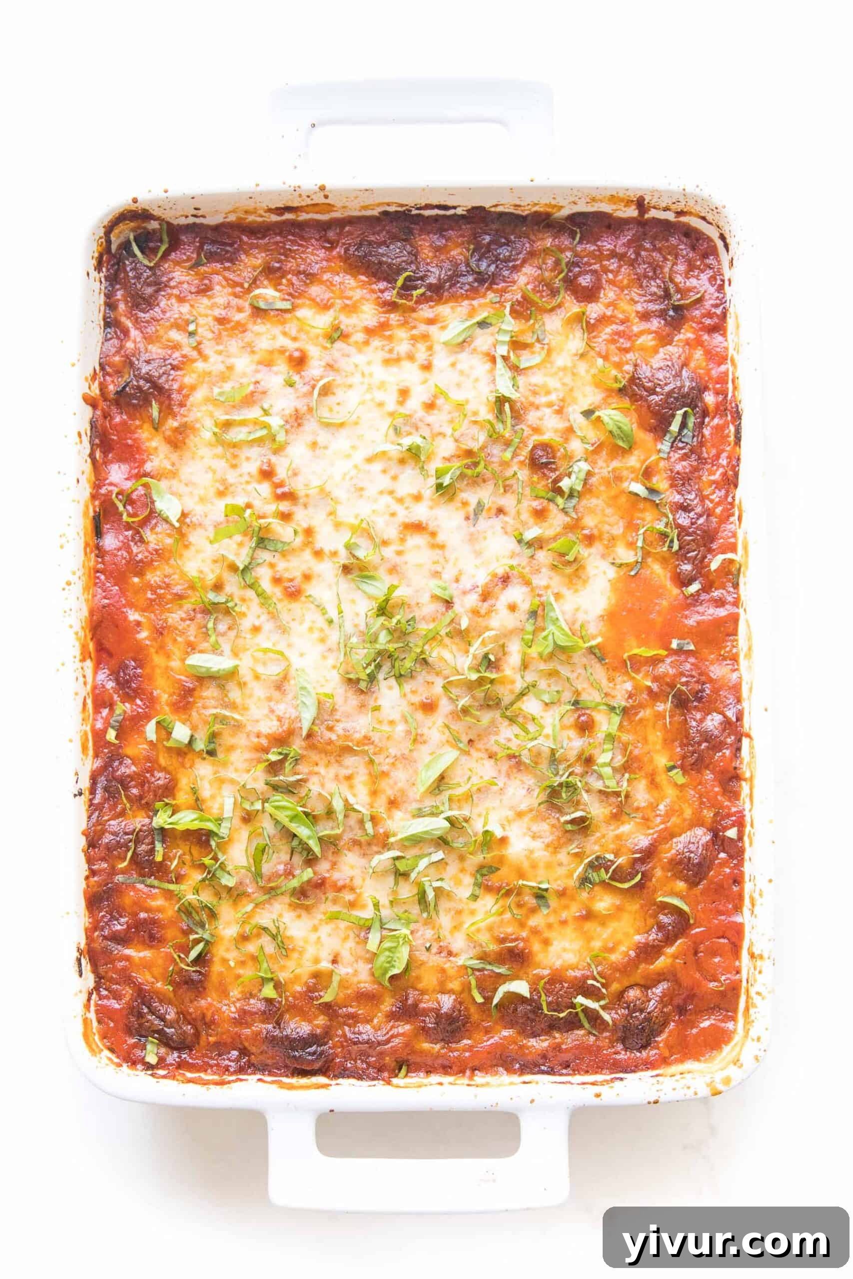 keto low carb lasagna made with zucchini noodles in a white baking dish topped with basil