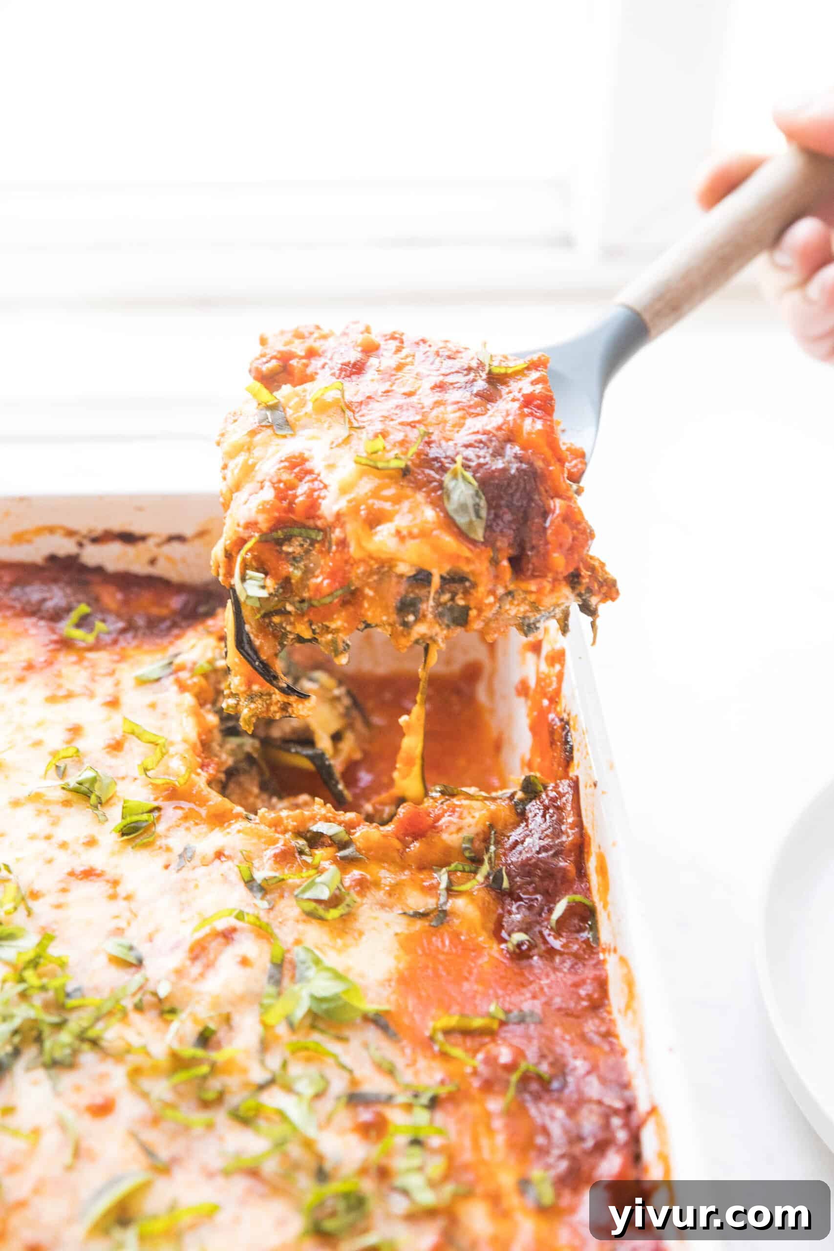 spooning out a portion of keto low carb lasagna made with zucchini noodles from the baking dish