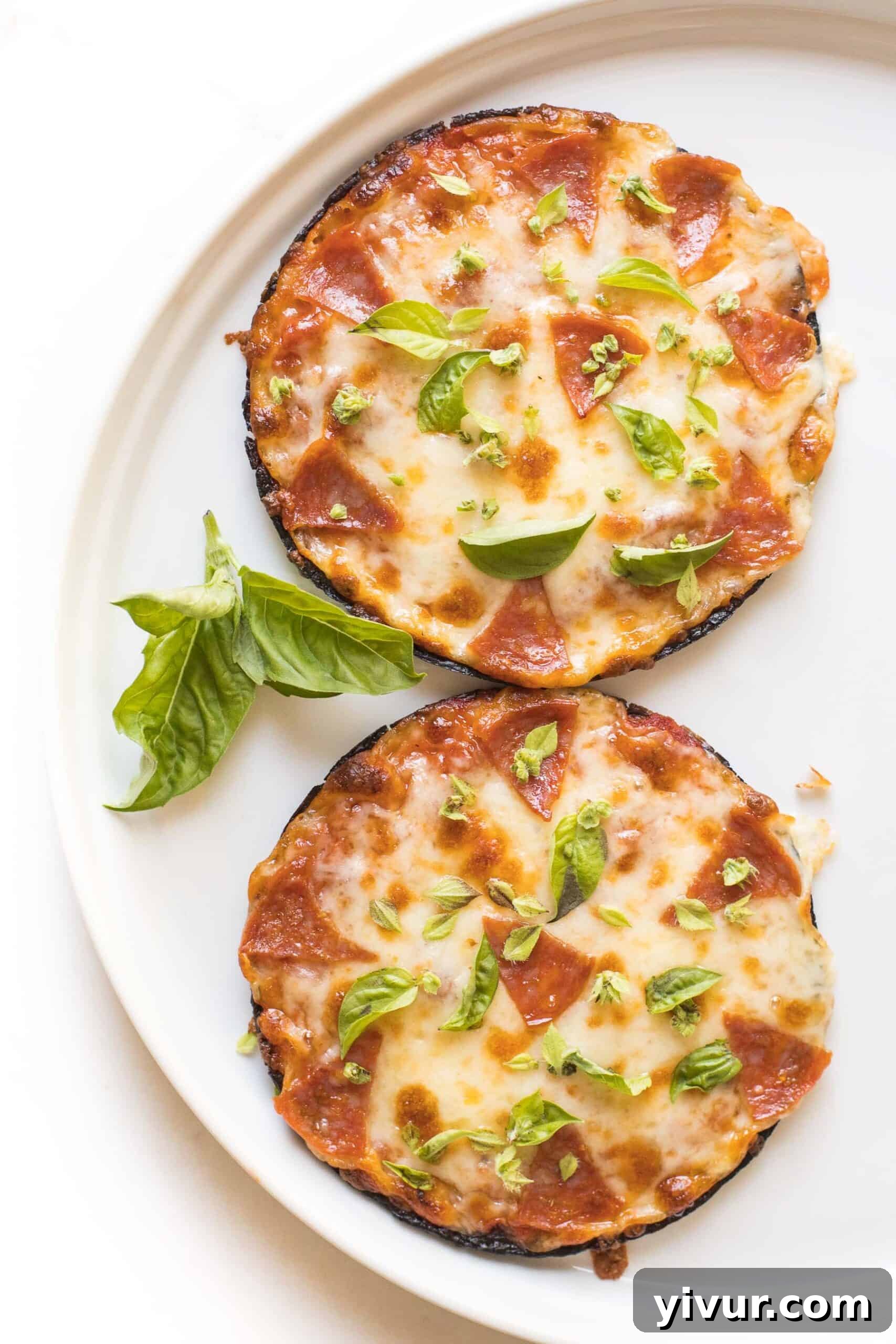 Close-up of a keto mini cauliflower thin pepperoni pizza on a white plate, highlighting the melted cheese and crispy pepperoni.