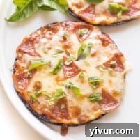 Keto Mini Cauliflower Thin Pizzas, garnished with fresh basil.
