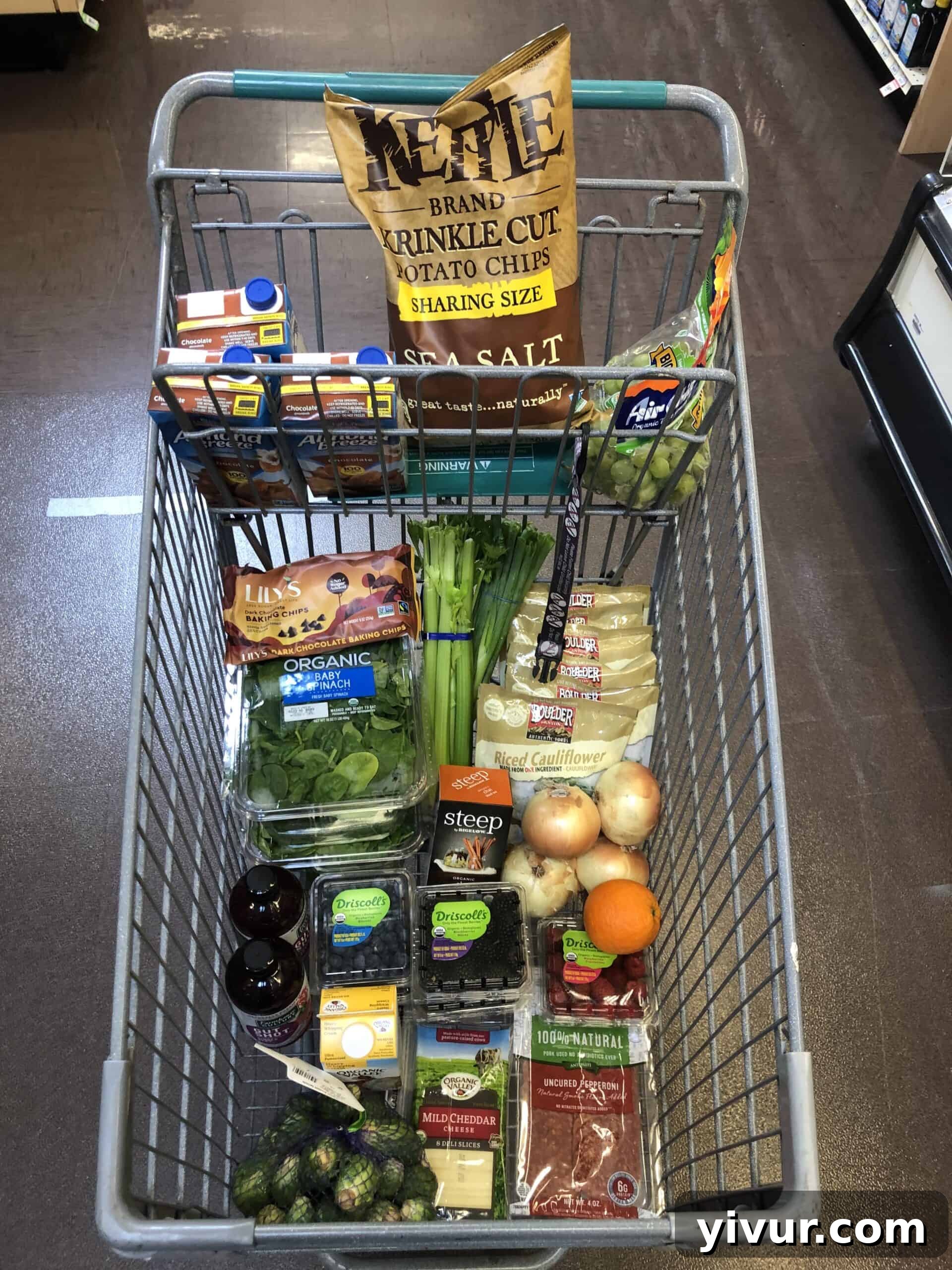A full grocery cart displaying a diverse selection of fresh produce, pantry staples, and keto-friendly items from a Sprouts grocery haul.
