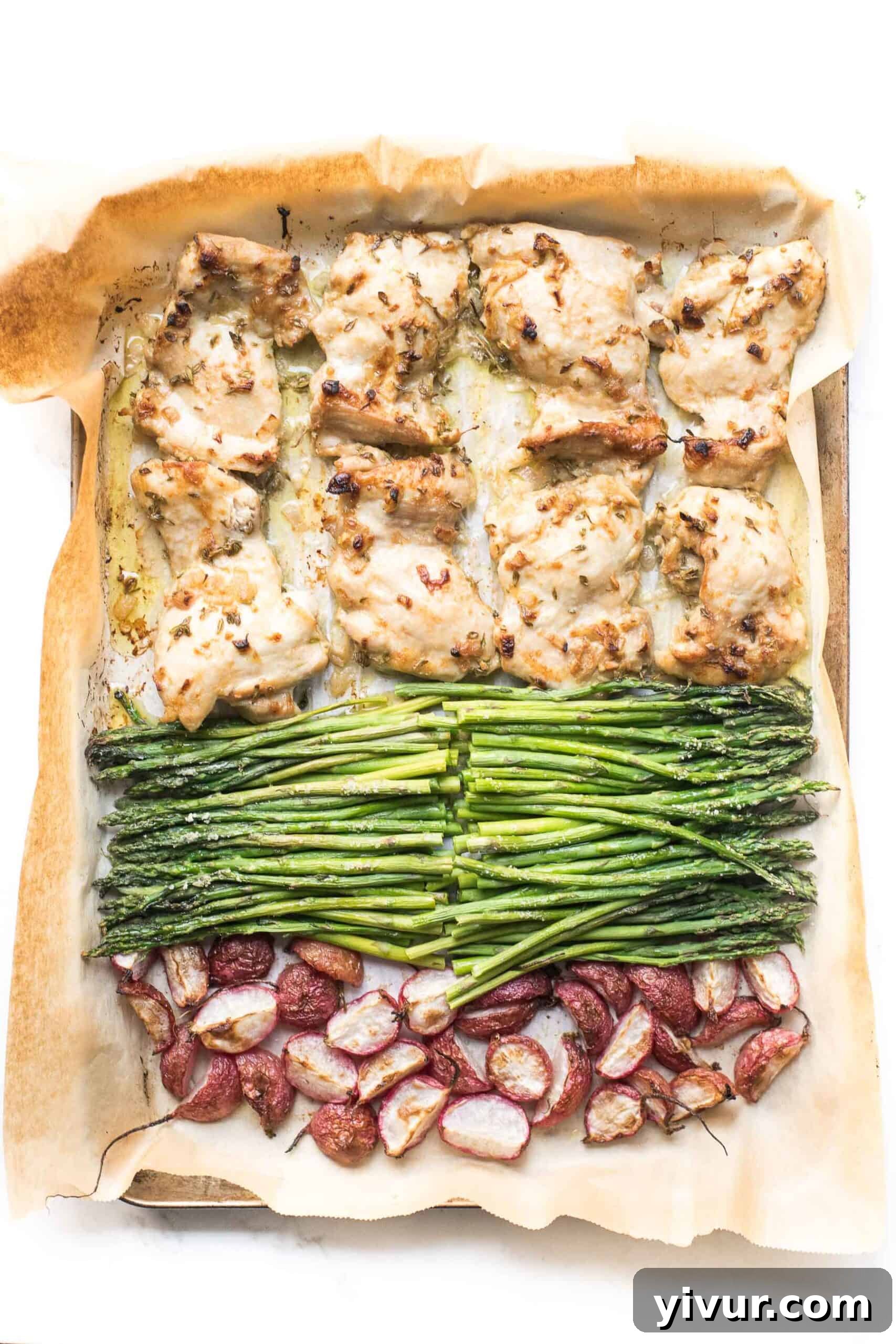 Sheet pan dinner featuring golden brown dijon mustard chicken thighs, roasted radishes, and vibrant green asparagus arranged on a baking sheet, ready to serve.