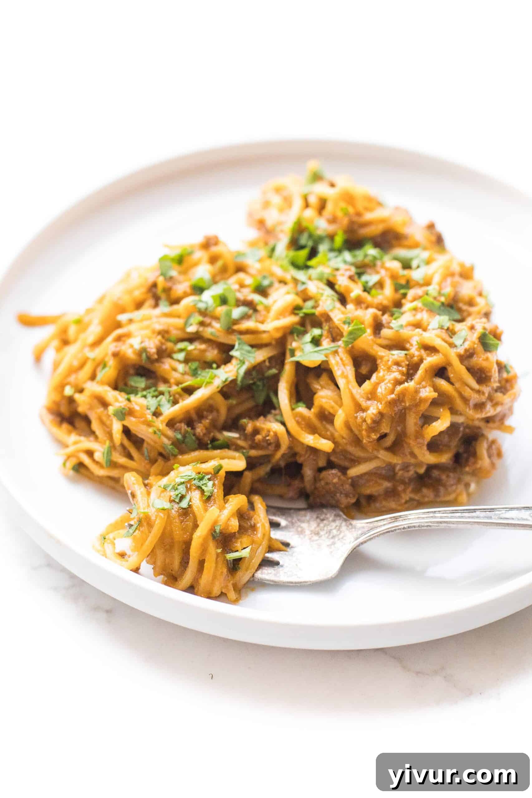 Guilt Free Whole30 Keto Spaghetti with Meat Sauce 2 Hearts of palm pasta with rich red meat sauce on a white plate, garnished with fresh herbs.