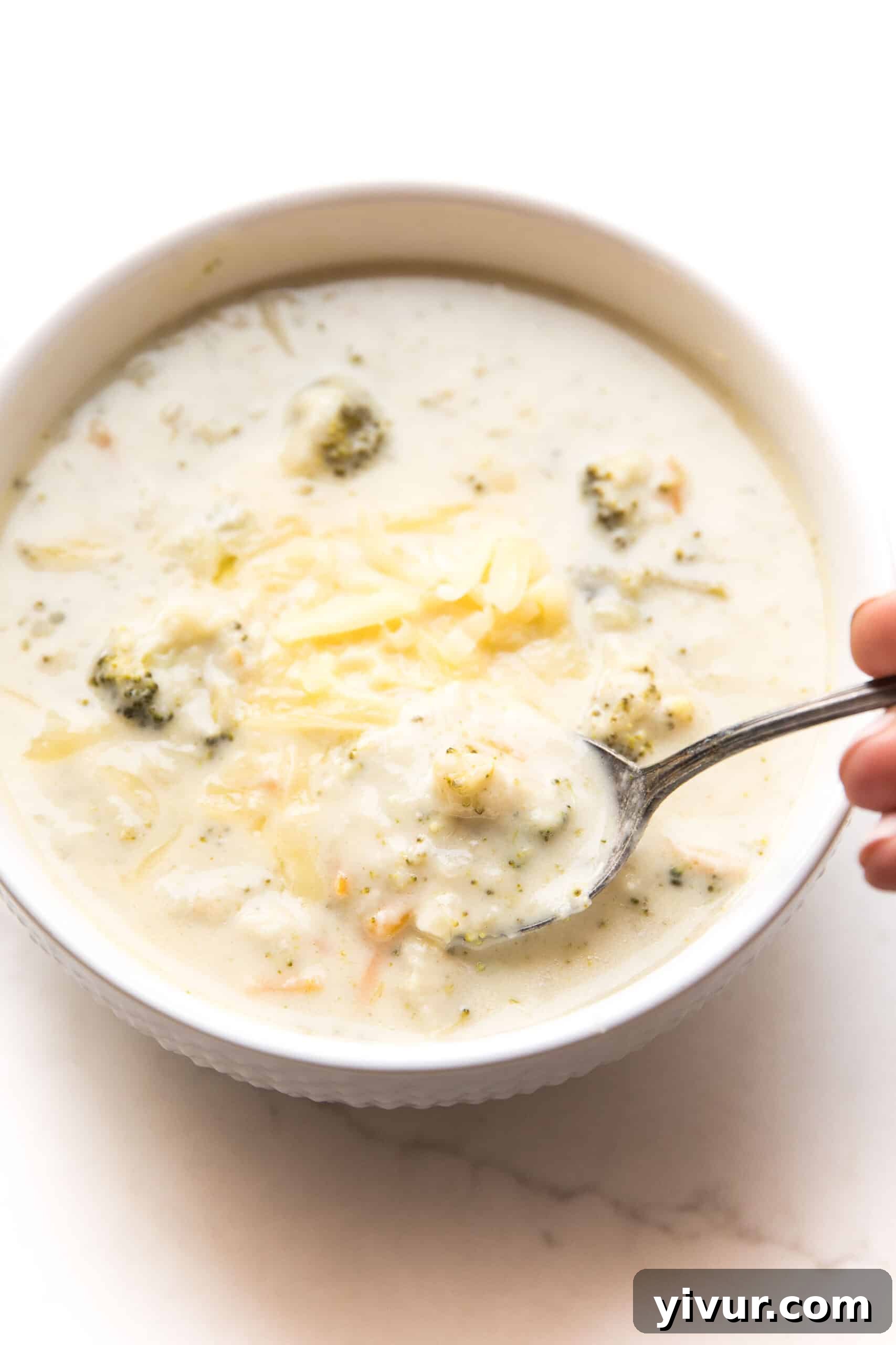 Instant Pot Keto Broccoli Cheddar Soup in a white bowl, garnished with fresh parsley.