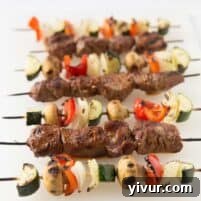 Close up of a single grilled steak and vegetable kabob, showcasing the marinade and char