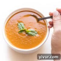 A bowl of creamy Whole30 + Keto Roasted Tomato Basil Soup with fresh basil garnish