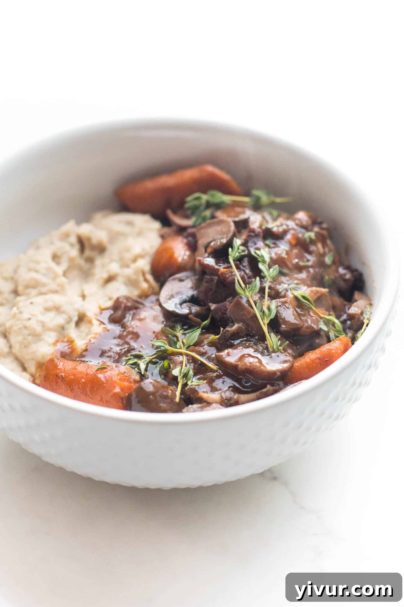 keto instant pot coq au vin with mashed cauliflower in a white bowl on a white background