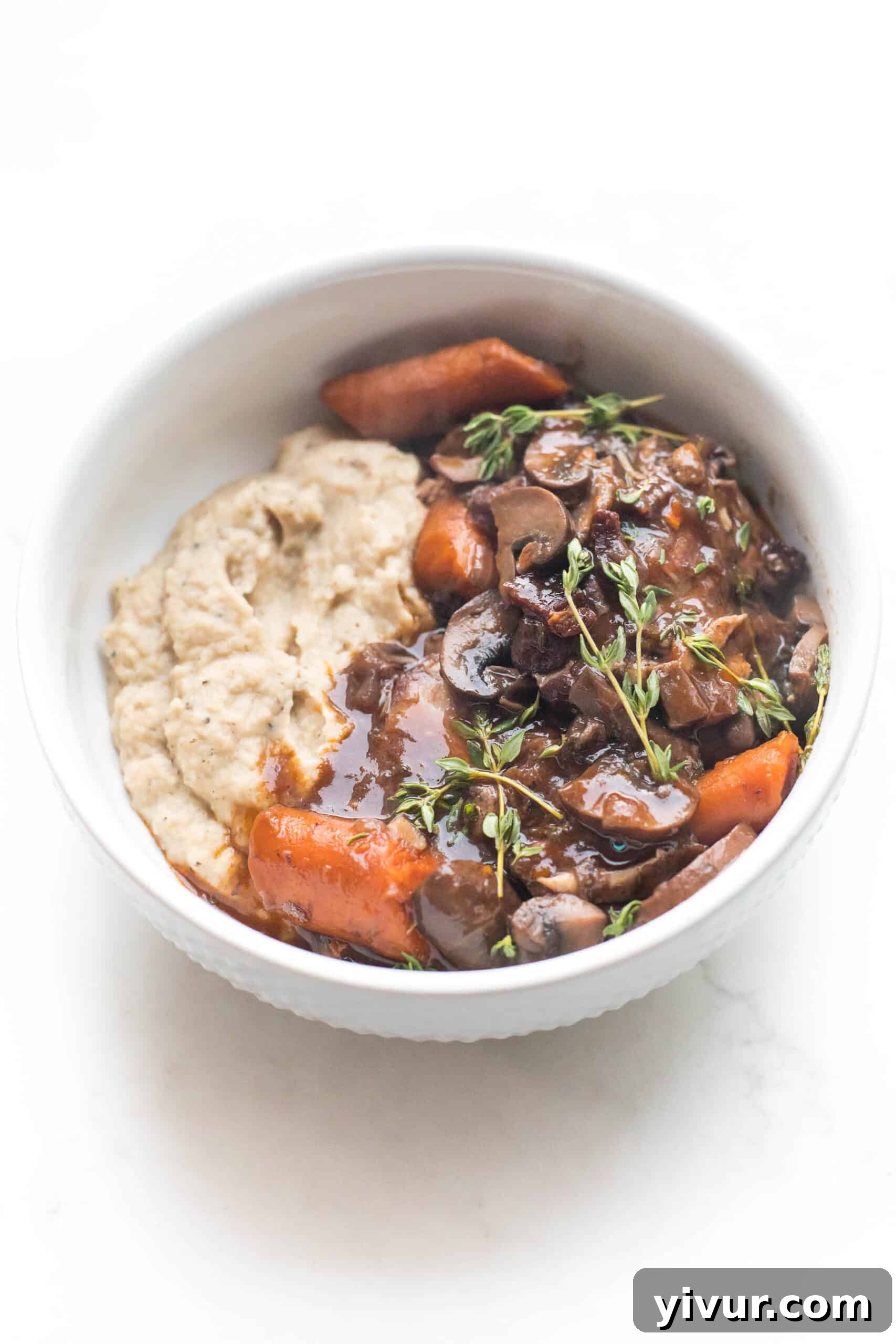 keto instant pot coq au vin with mashed cauliflower in a white bowl on a white background