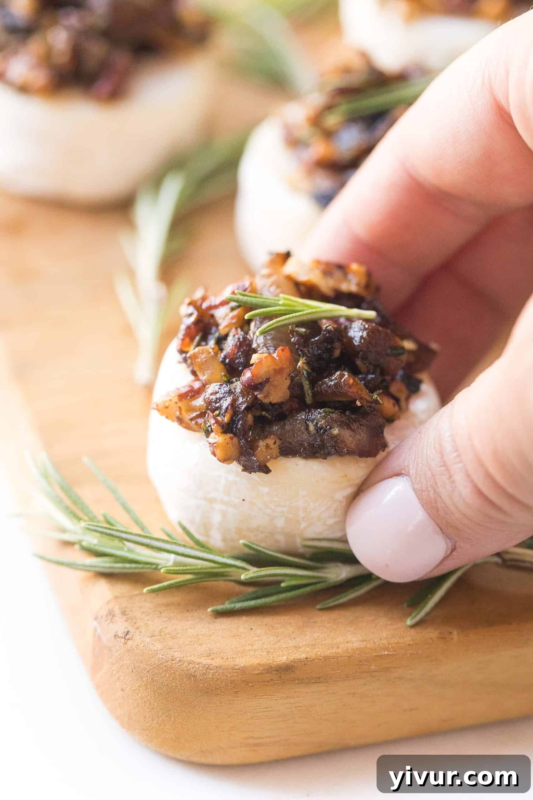 A festive cheese board featuring Keto Caramelized Onion + Rosemary Brie Bites, garnished with fresh rosemary sprigs and whole pecans, ready for holiday serving.