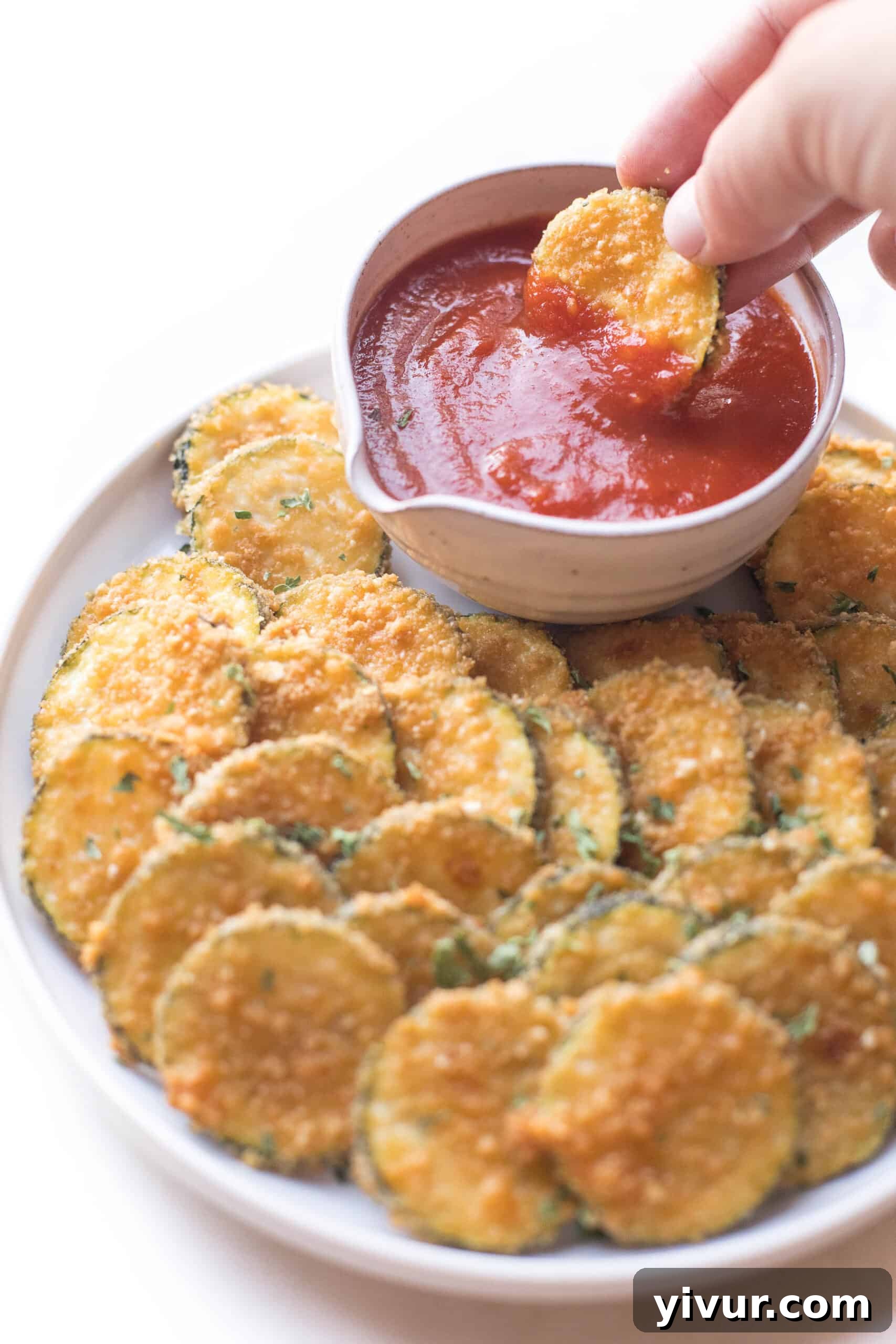 Crispy parmesan zucchini bites appetizer being dipped in marinara sauce