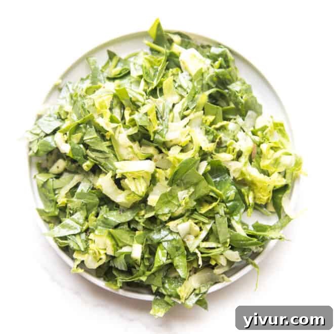 A simple yet elegant green house salad on a white plate and background.