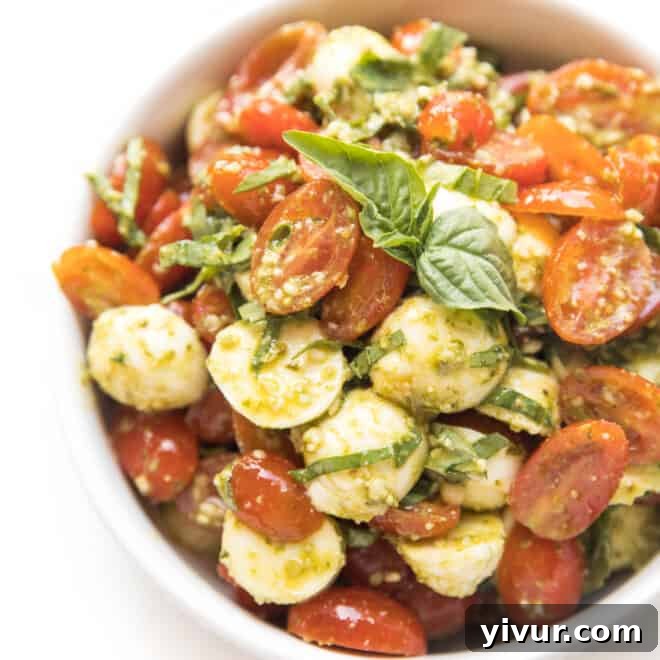 A vibrant Keto Pesto Caprese Salad with fresh tomatoes, mozzarella, and basil.