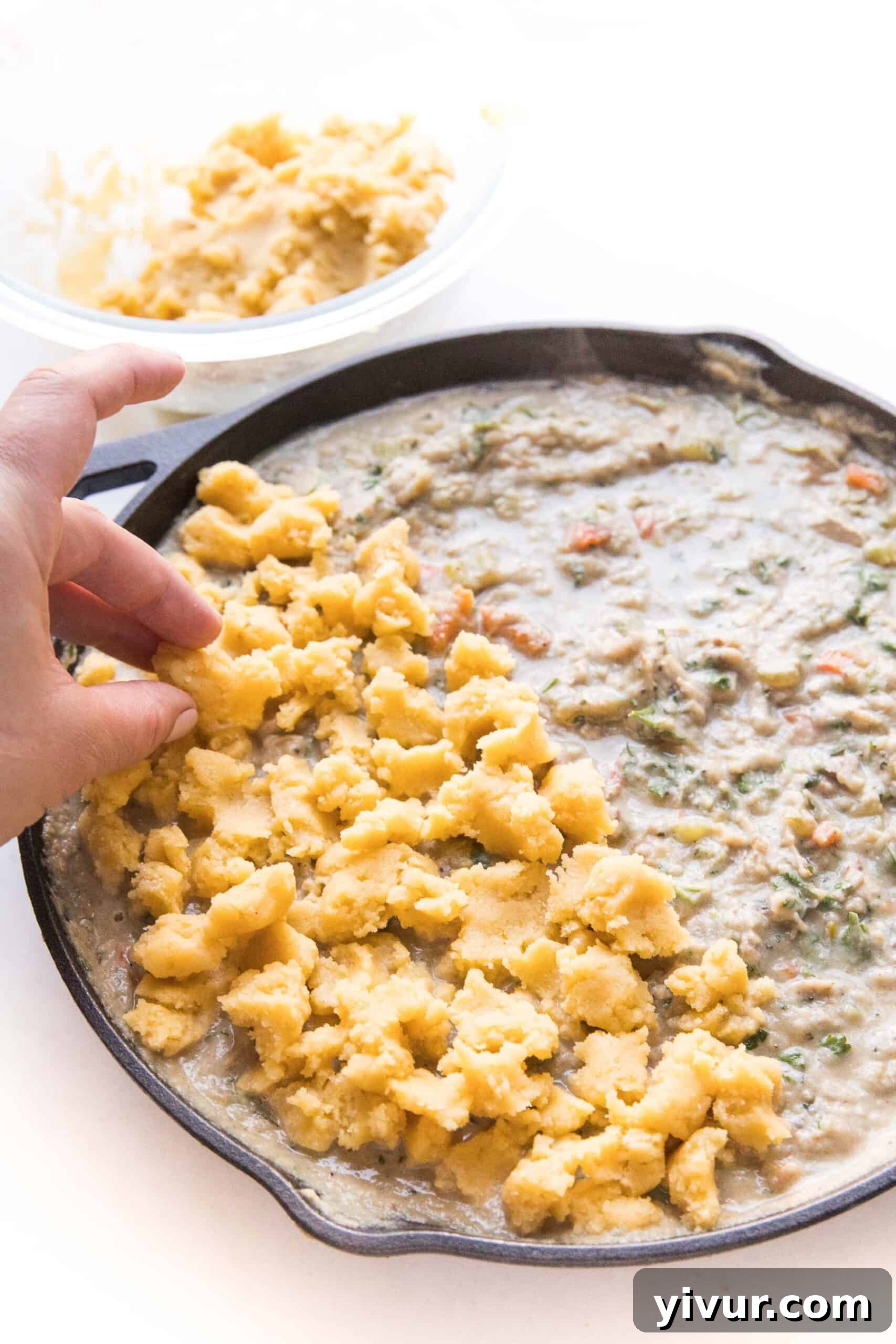 Closeup view of the rich and creamy Keto Chicken Pot Pie Crumble filling in a cast iron skillet before adding the topping