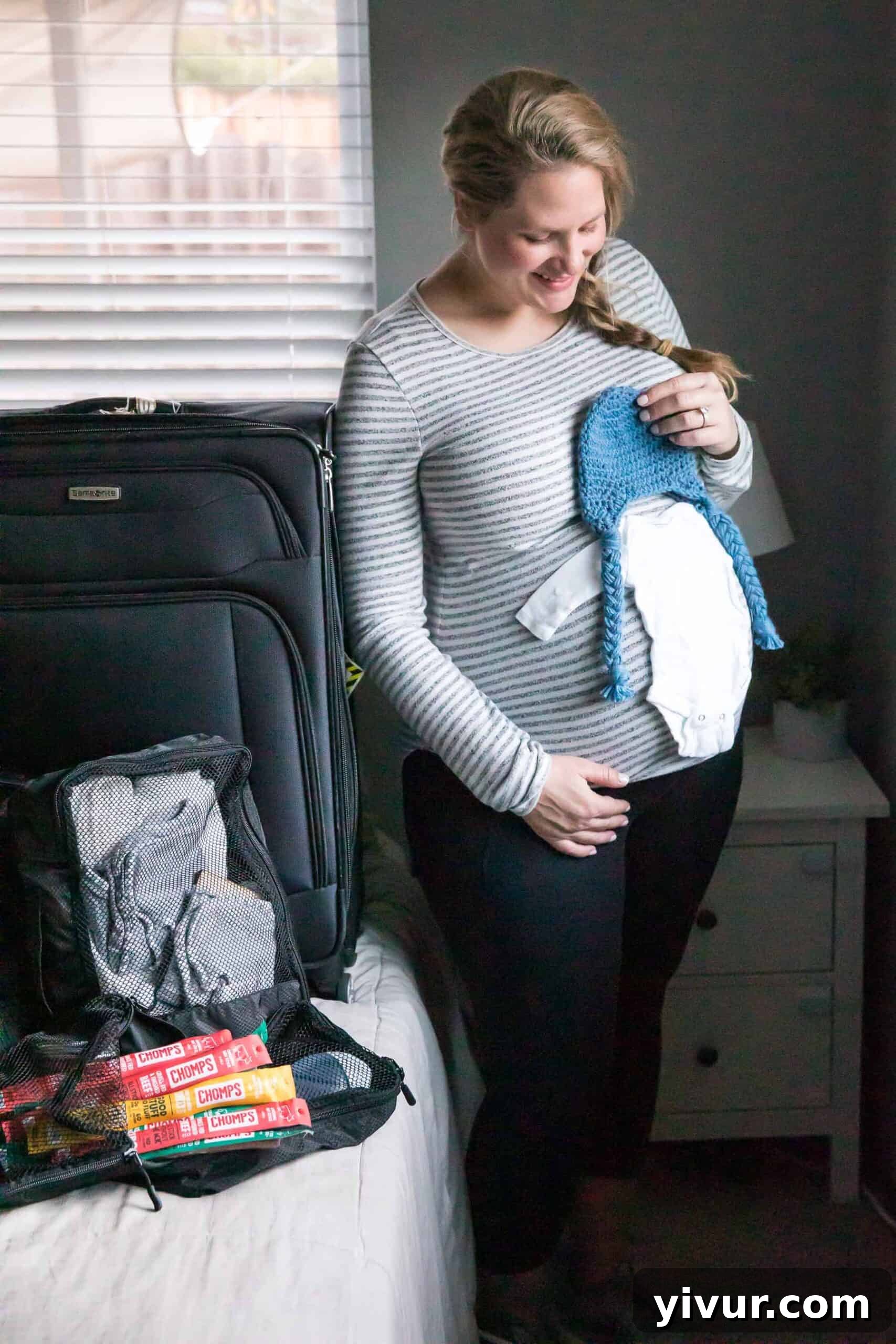 My Go-Bag for Baby's Arrival 2 pregnant girl standing next to hospital bag holding up baby clothes