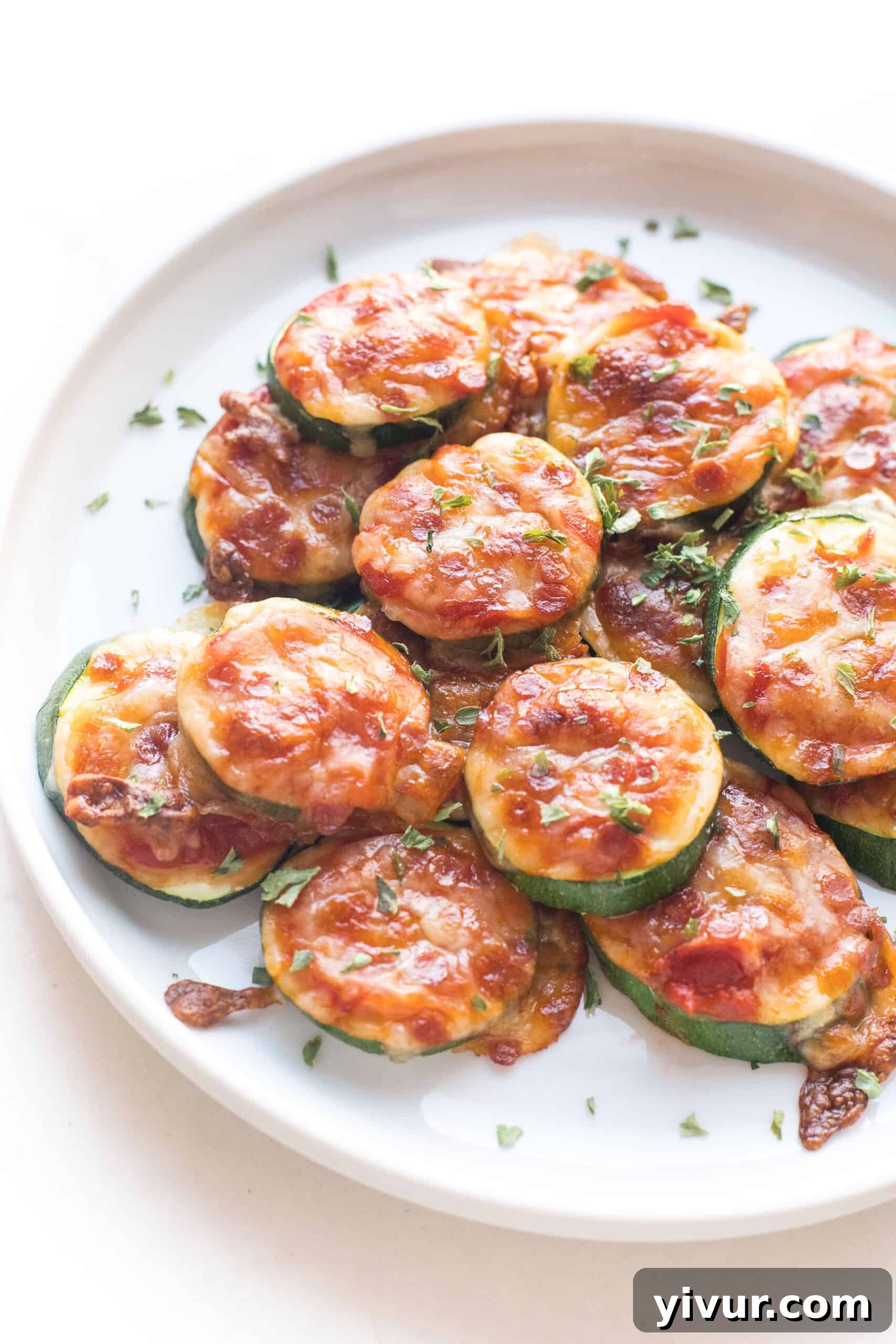 keto mini zucchini pizza bites on a white plate and background