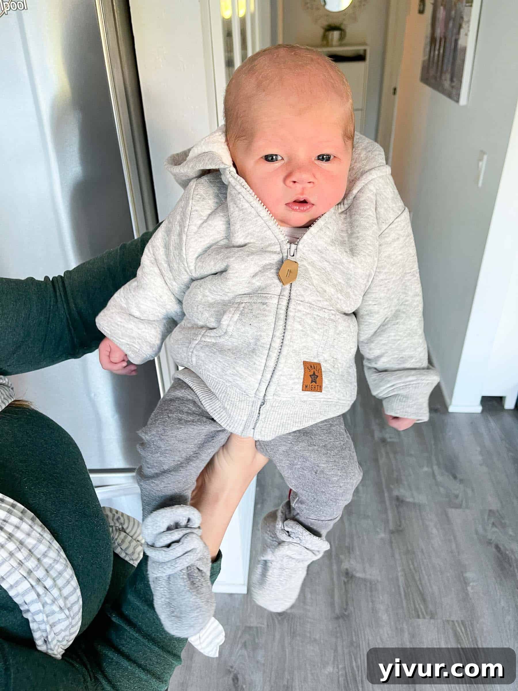 A tender photograph of a parent holding Luke, focusing on the intimate connection and comfort between parent and newborn.