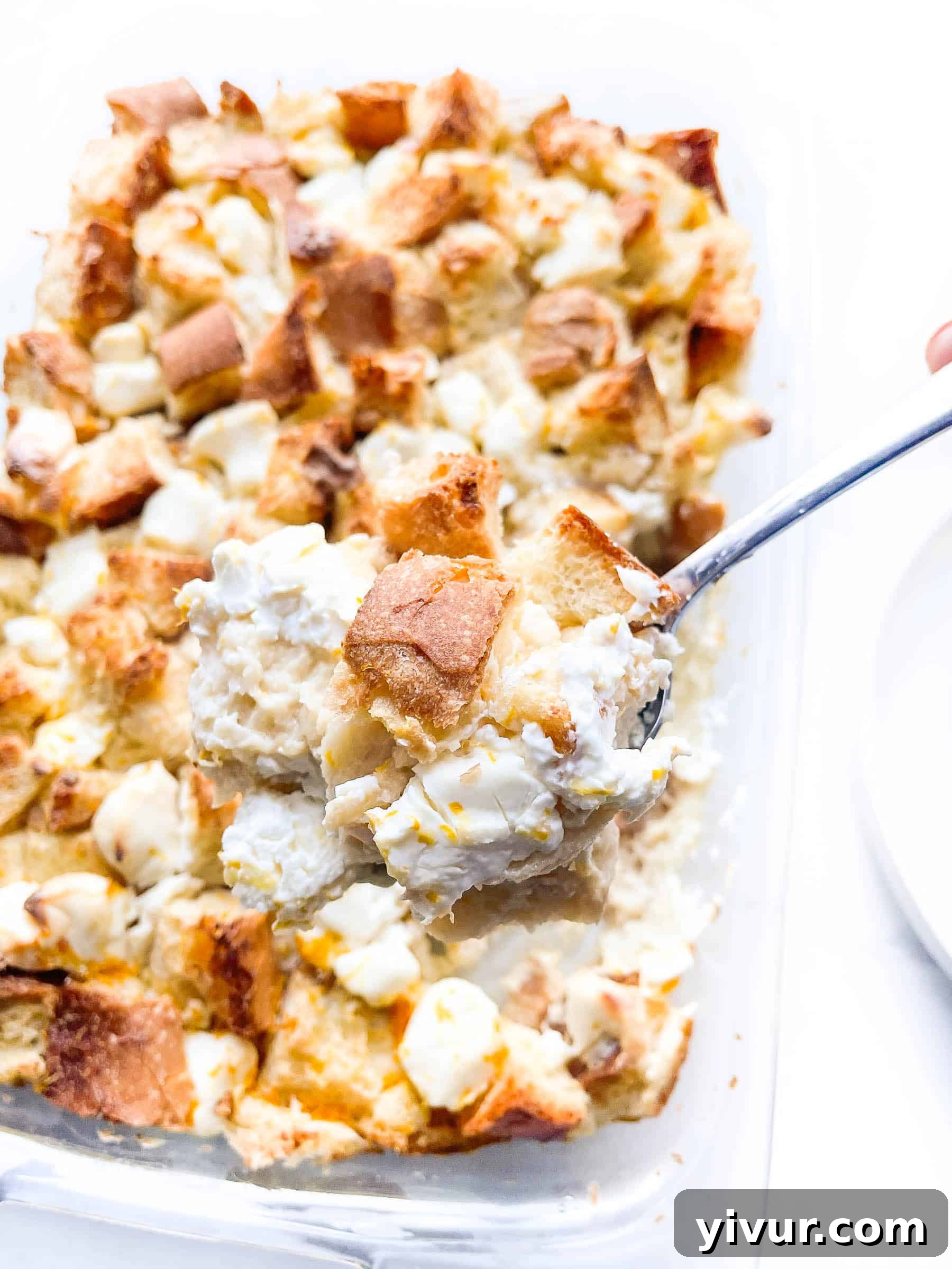 Glass baking dish filled with cubed bread and cream cheese, soaking in the custard mixture overnight