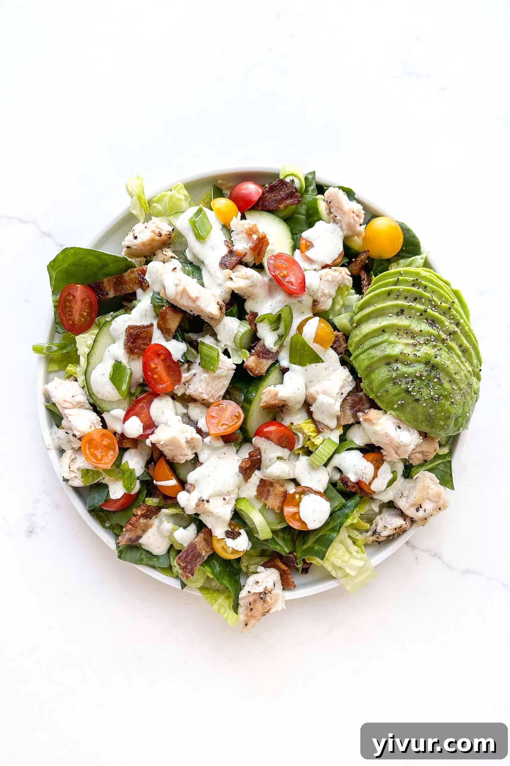 Keto BLT Ranch Chop 2 A vibrant Keto Ranch BLT Chopped Salad, featuring fresh greens, crispy bacon, tender chicken, diced tomatoes, and avocado slices, generously drizzled with creamy ranch dressing, presented in a large bowl.