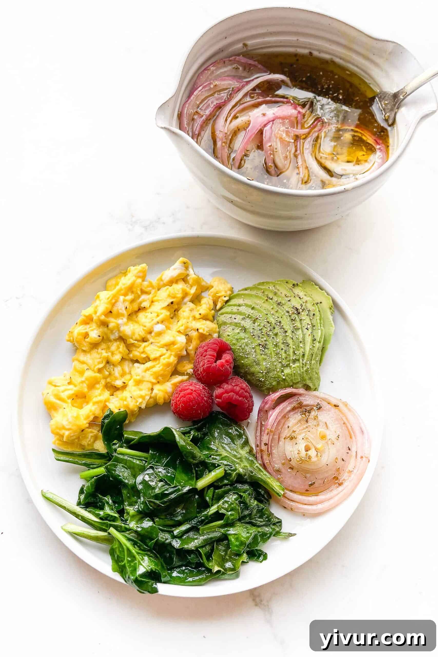 Keto Soft Scrambled Eggs with Spinach and Tangy Marinated Onions 3 Close-up view of the keto breakfast, highlighting the soft texture of the eggs, the vibrant green of the spinach, the creamy avocado, and the striking red of the marinated onions, with a few raspberries for color.