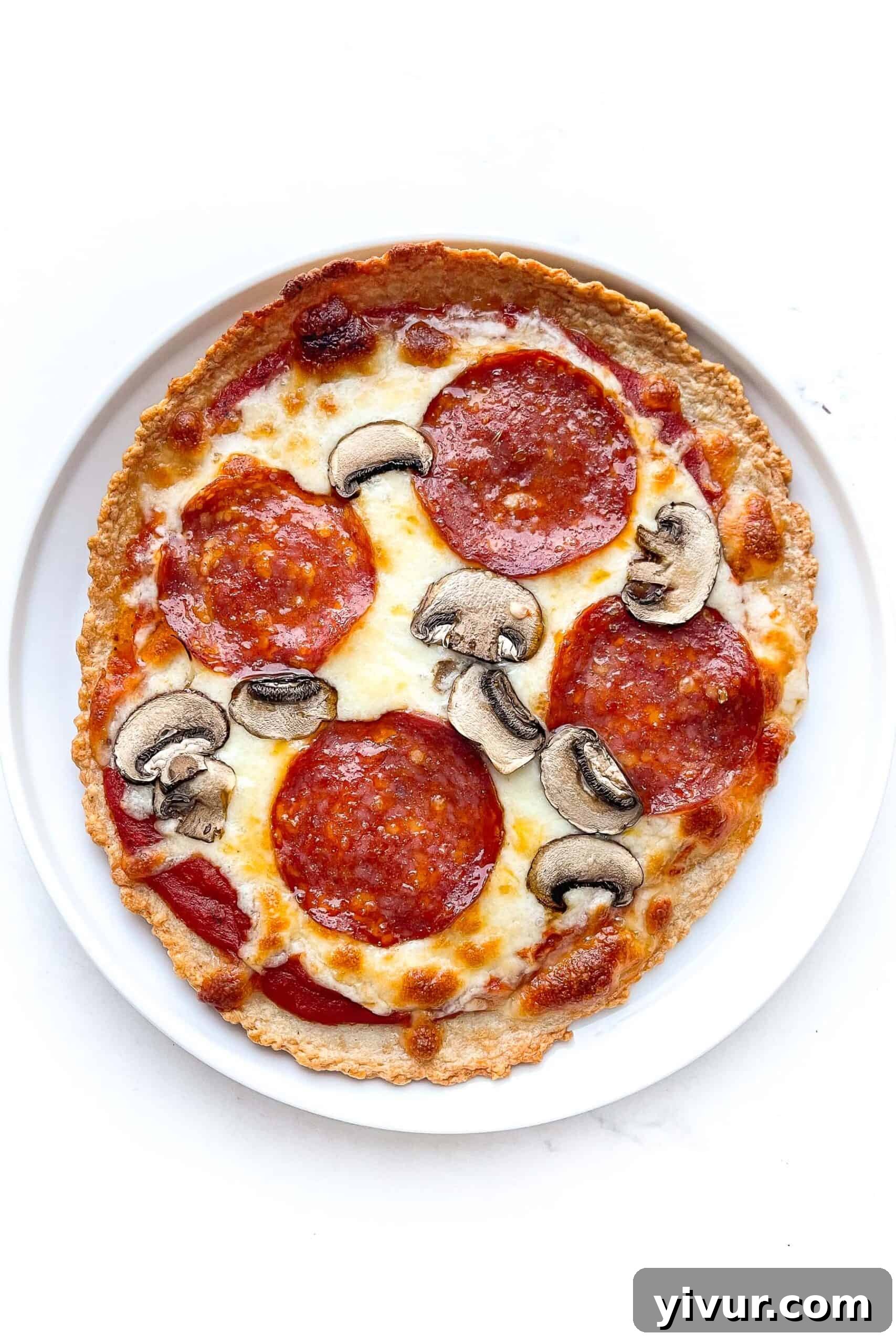 Delicious zero carb pepperoni and mushroom pizza on a white plate against a clean background